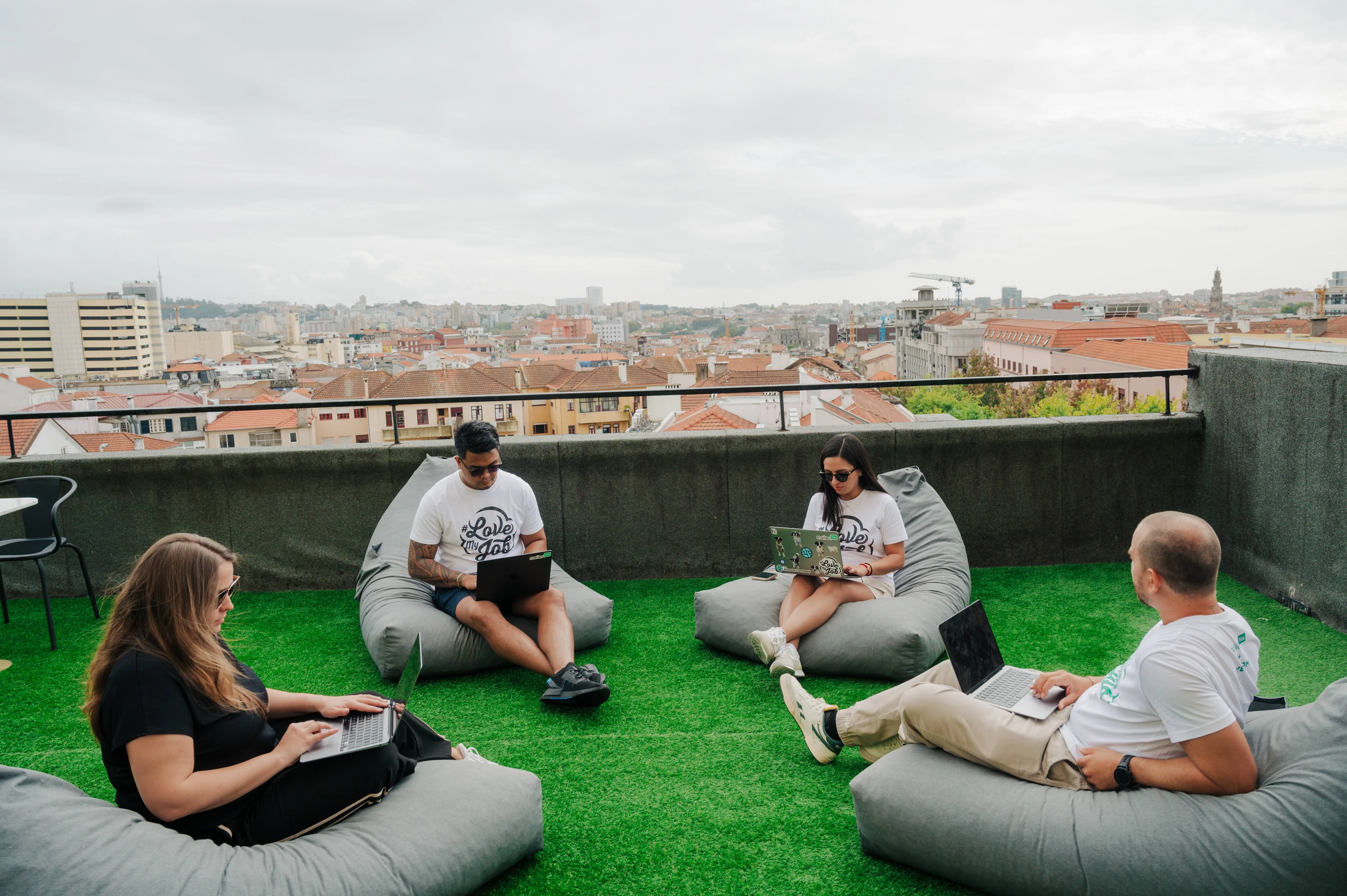 Four people sitting outside with laptops