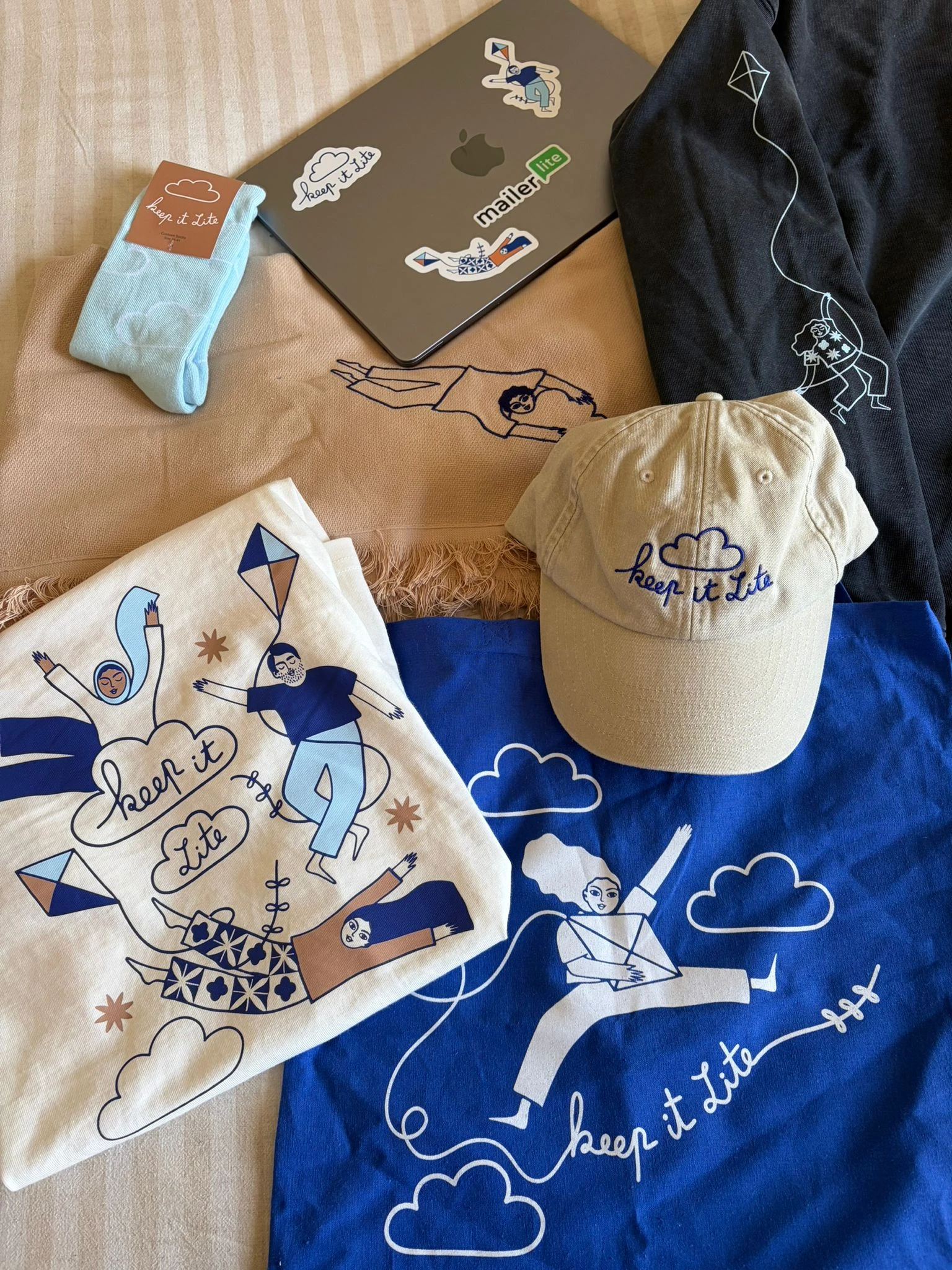 Photo showing the hats, t-shirts, socks, and laptop stickers designed by Sakina Saïdi
