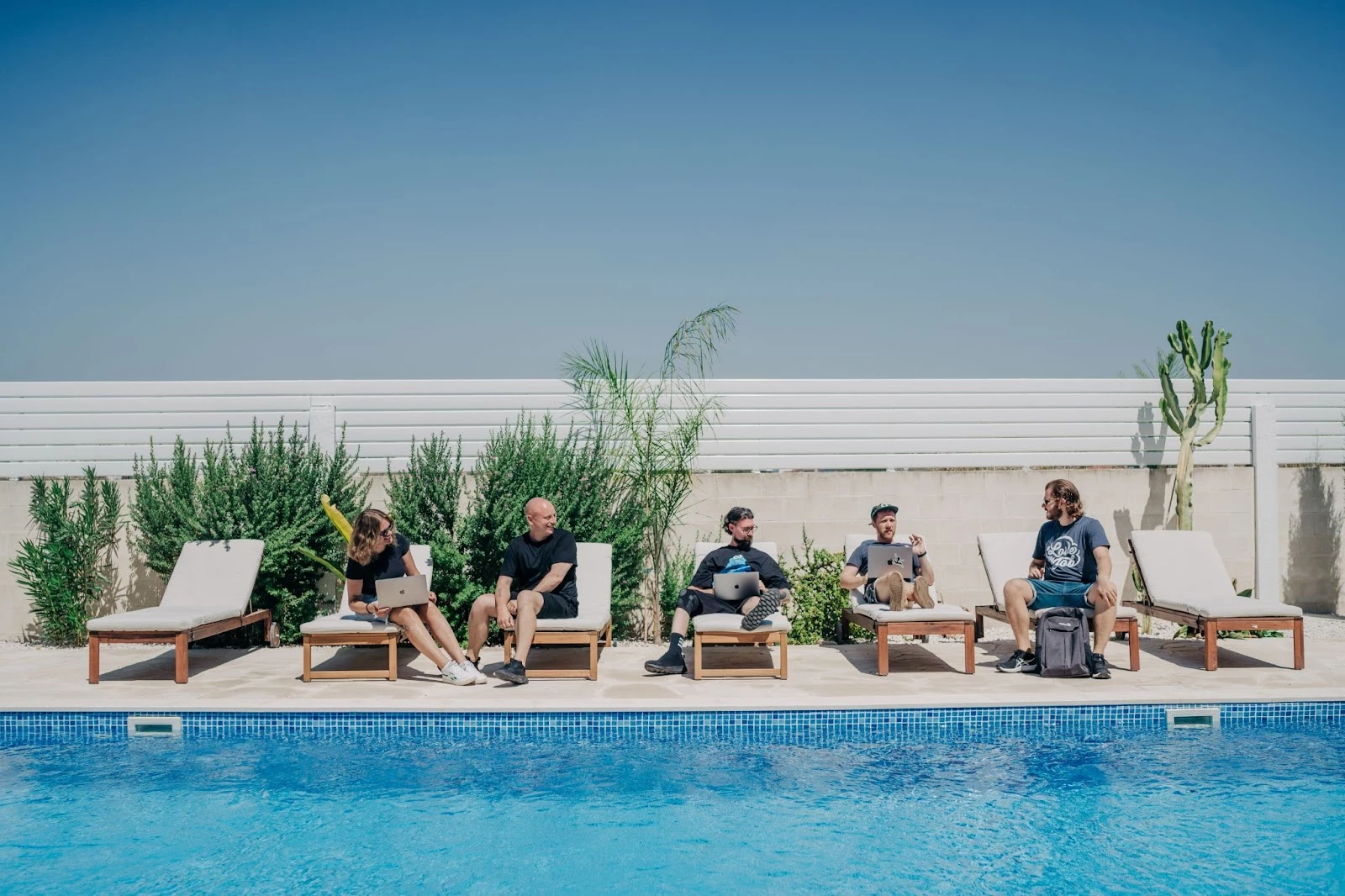 Group of people working on laptops near the pool